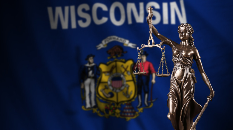 Wisconsin state flag behind Lady Justice