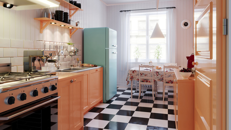 Kitchen with pastel green refrigerator and orange cabinets.
