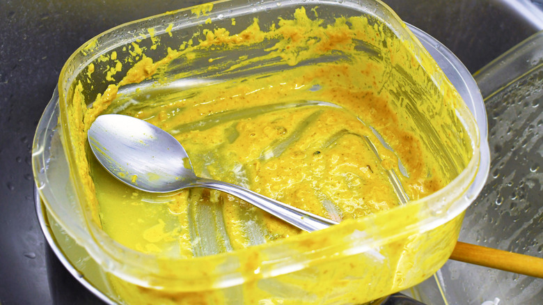 A dirty plastic food conainer with curry sauce.