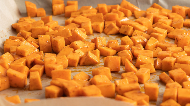 Cubed sweet potatoes on a parchment-lined sheet pan