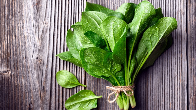 An illustrative image showing a fresh bundle of spinach on a wooden surface.