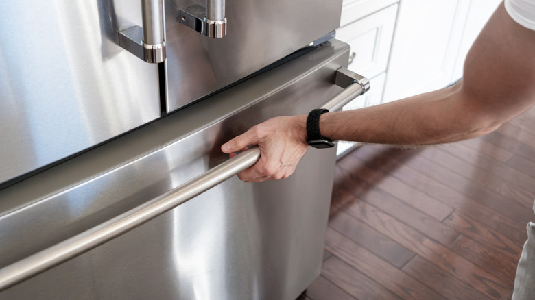 Tangan manusia membuka pintu freezer