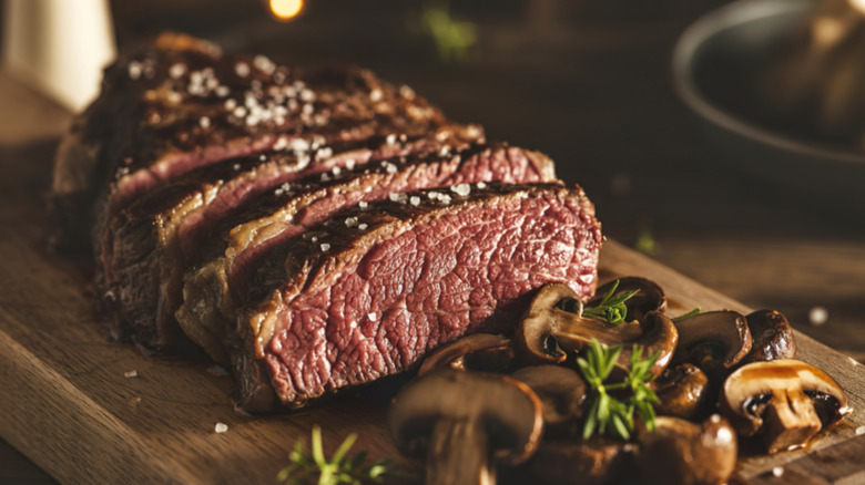 A partially sliced, medium rare ribeye steak