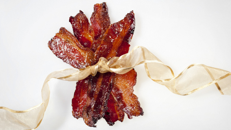Candied bacon wrapped into a bundle with a gold ribbon