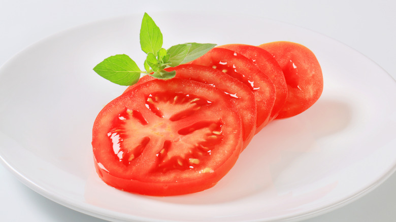 sliced tomato and basil on white plate