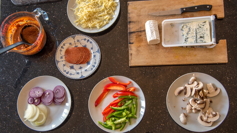 A selection of pizza toppings laid out on plates.