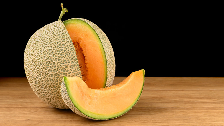 A cantaloupe sliced on a wooden table.