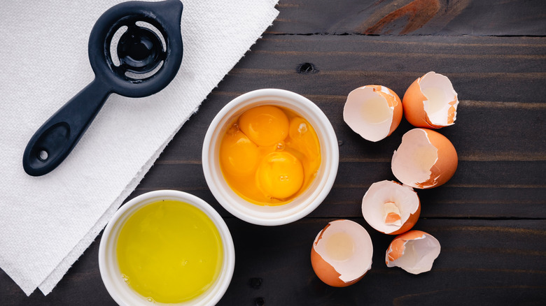 a black egg separator beside egg whites and egg yolks on brown table