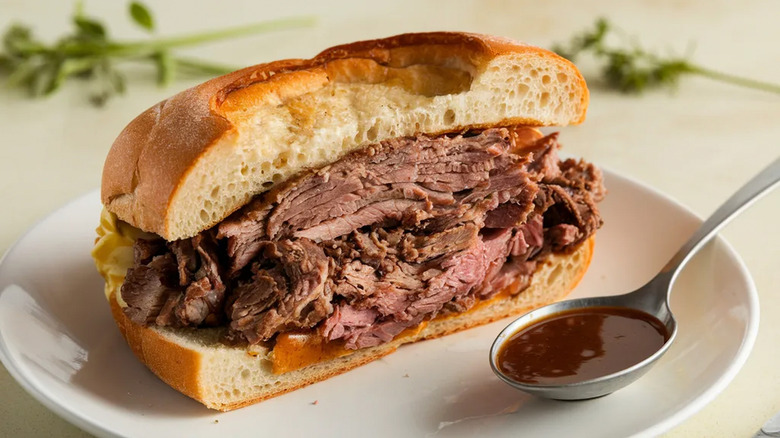 A roast beef sandwich has been sliced in half.