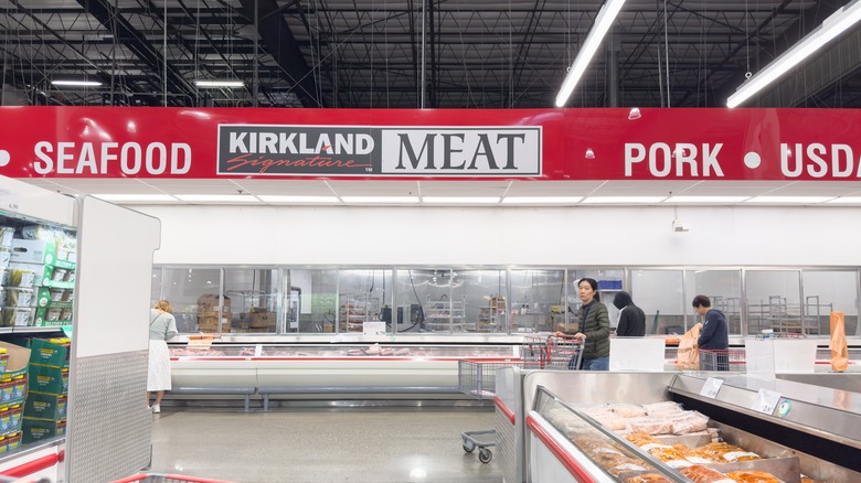 Costco meat aisle with a few shoppers pushing their carts