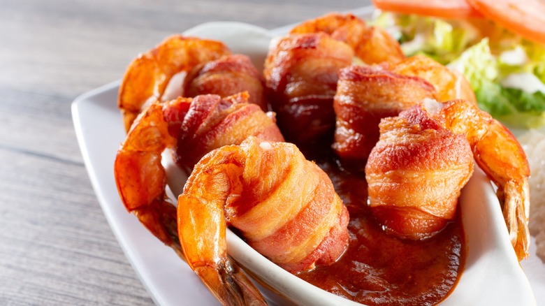 Bacon-wrapped shrimp in sauce bowl