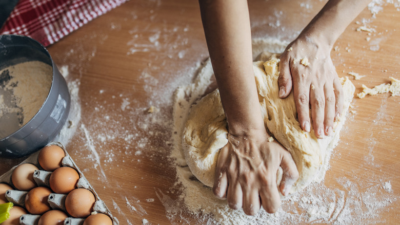 A woman kneading dough on a wooden table