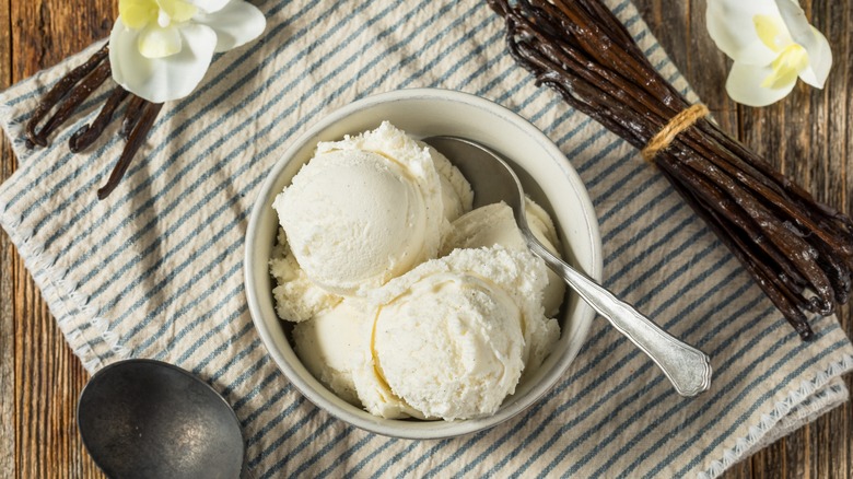 French vanilla bean ice cream in a bowl with vanilla pods and flowers