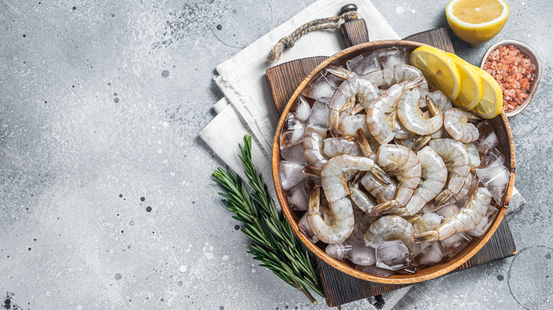 Uncooked shrimp in a bowl on a gray background.