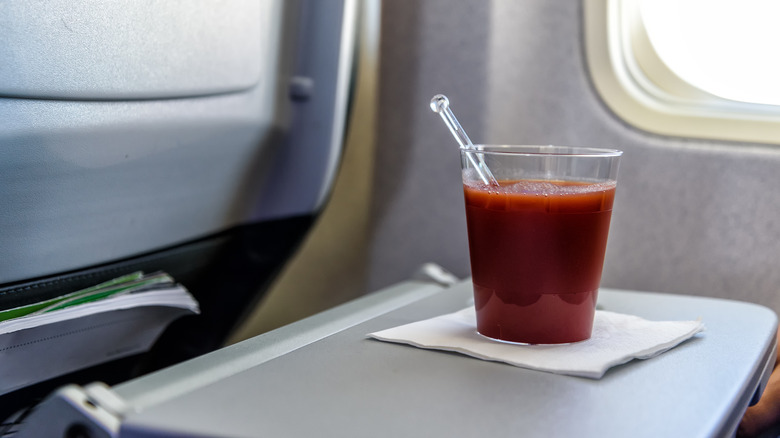 Cup of tomato juice on airplane seat tray