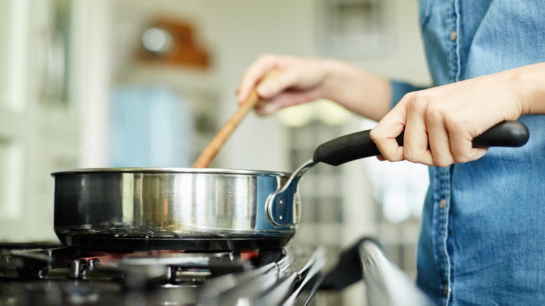 Woman stirring sauce in saucepan