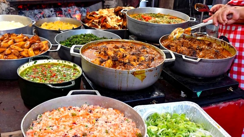 Various pots of food cooking on an outdoor stove.