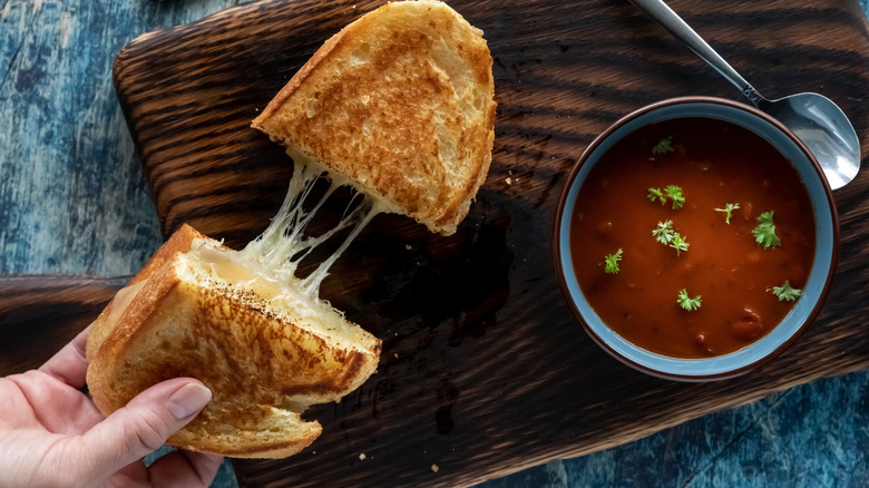 Grilled cheese sandwich being pulled apart on wooden surface