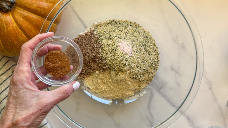 hand adding spices to bowl with flour and ground flax seed