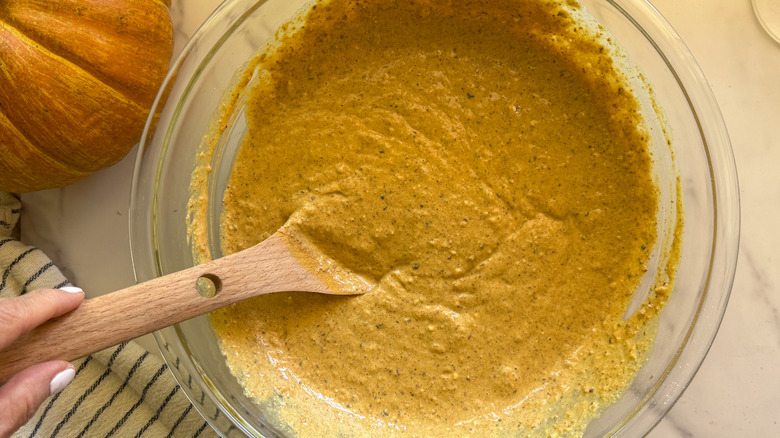 hand holding spoon in pumpkin muffin batter