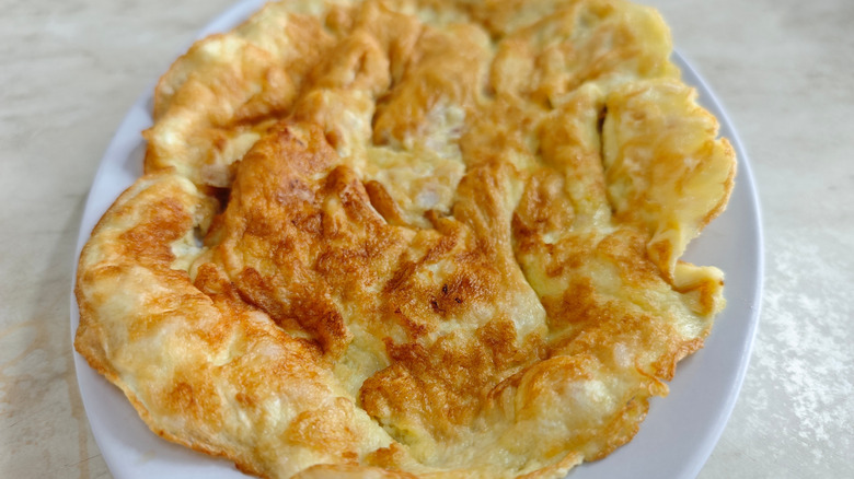 A fluffy, golden-brown omelet served on a light-colored plate.