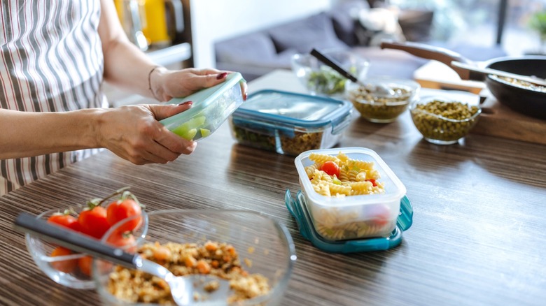 Woman meal prepping various foods in containers