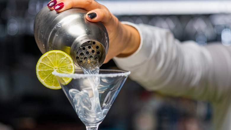 Margarita being poured from a cocktail shaker into a glass.