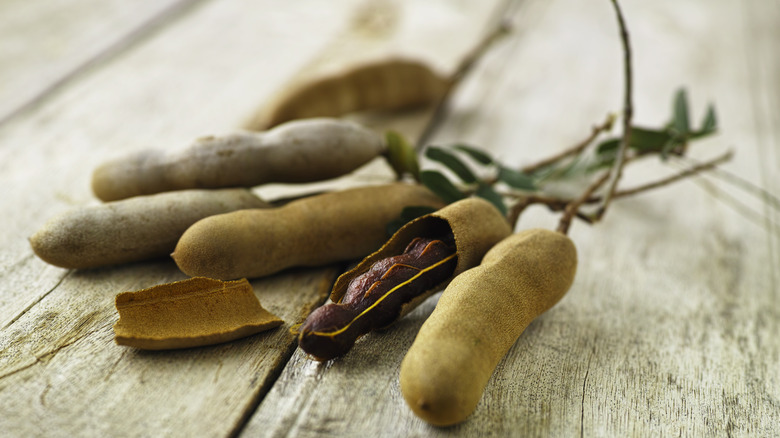 Freshly picked tamarind fruits on a wooden table.