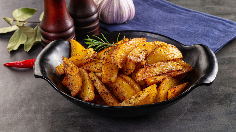 Seasoned roasted potatoes with herbs in a black dish