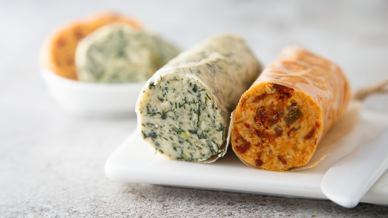 Homemade compound herb butters rolled in baking paper.