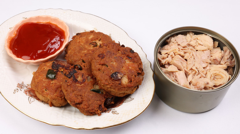 Cooked tuna patties next to a can of open tuna.