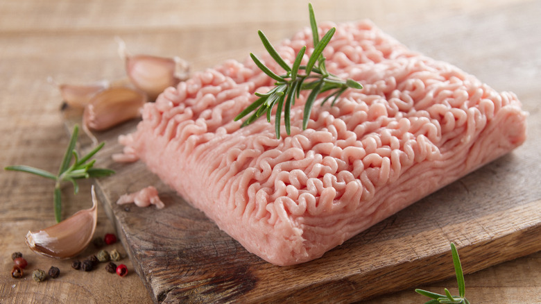 A block of raw ground turkey dressed up with herbs and garlic cloves.