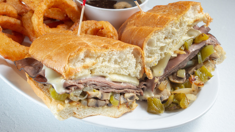 Cheesesteak sandwich cut in half on plate.