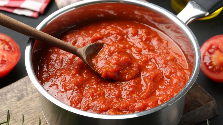 Homemade tomato sauce and spoon in pot on table, closeup