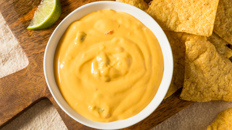 Queso dip with tortilla chips and a lime wedge.