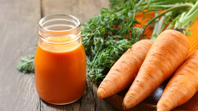 fresh carrots next to a jar of carrot juice