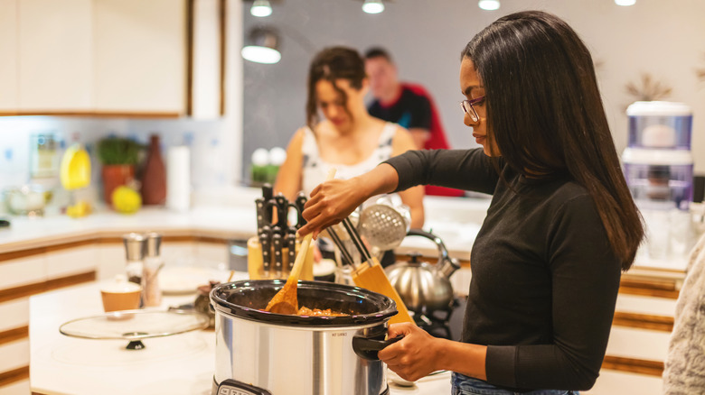woman stirring ingredients into a slow cooker