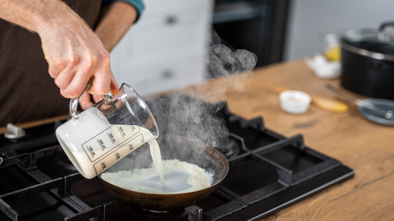 Hand pouring milk into a pan