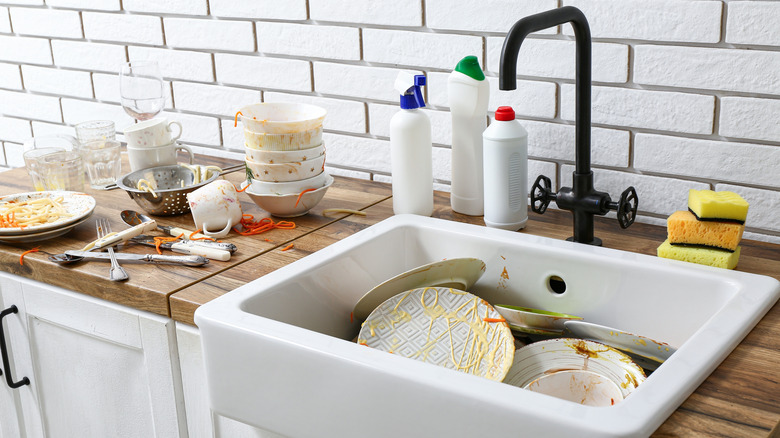 Cluttered kitchen sink with dirty dishes piled high