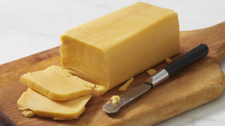 A block of American cheese on a wooden cutting board
