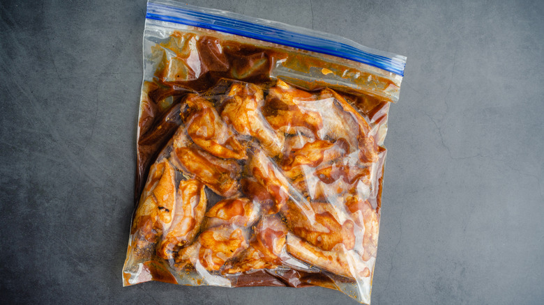 Raw chicken legs marinating in a Ziploc bag