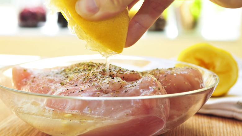 Lemon squeezed on raw chicken to marinate and infuse acidity