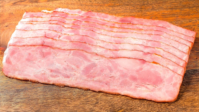 Stack of raw, unpackaged turkey bacon on a wooden surface