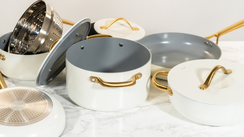 Various components of a ceramic cookware set including pots, lids, steamer insert, and frying pans.