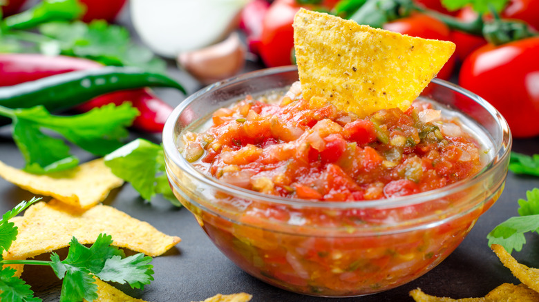 Chunky salsa in a glass bowl with a tortilla chip