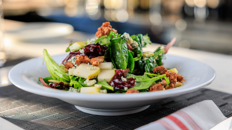 big salad with lots of ingredients on a white plate with a blurred background