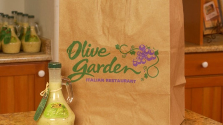 Olive Garden takeout bag next to salad dressing