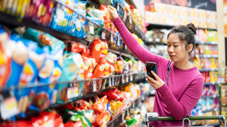 Woman at grocery store reaching for bag of chips