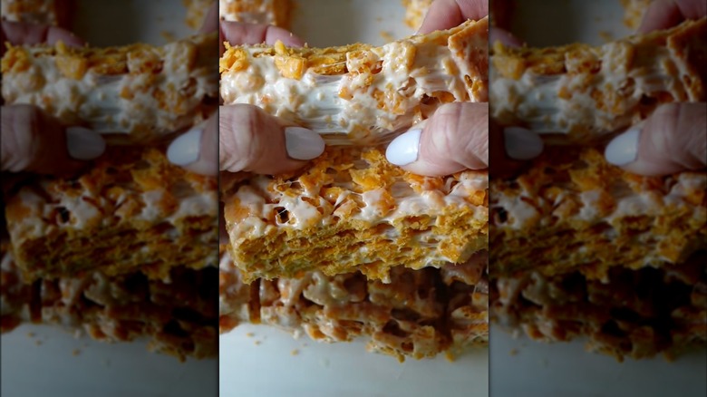 Hands pulling apart Cheez-Its marshmallow treat.