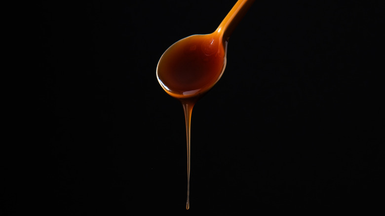 Caramel flowing from spoon with black background.